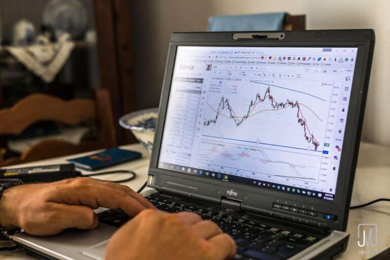 a man using laptop on which the stock trading graph is shown