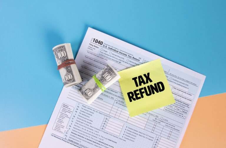 tax refund written on sticky note, a paper and roll money place on table with blue background