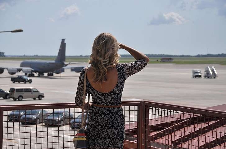 a girl waiting at the airport in curly hairs and black dress 