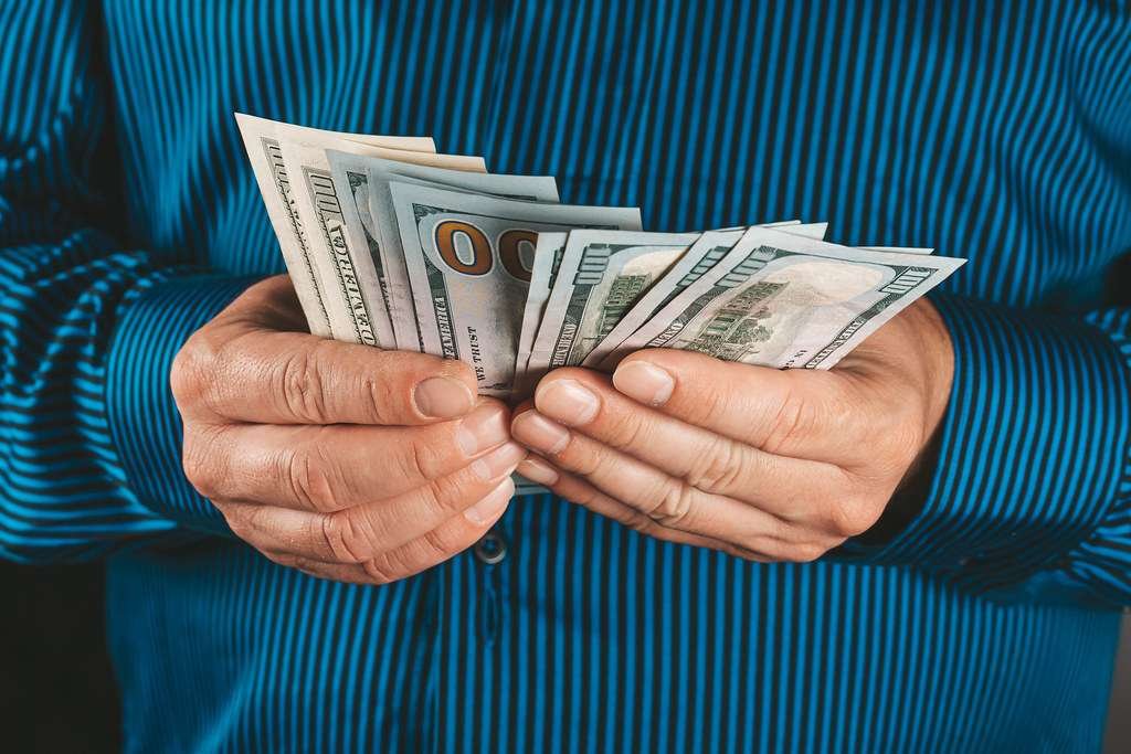 man holding money in hand with blue short