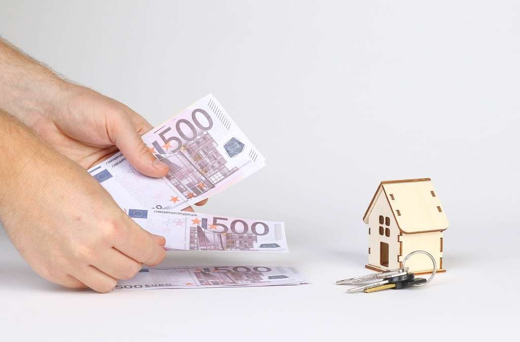 man placing money on table from his hand, a small house is on the white table 