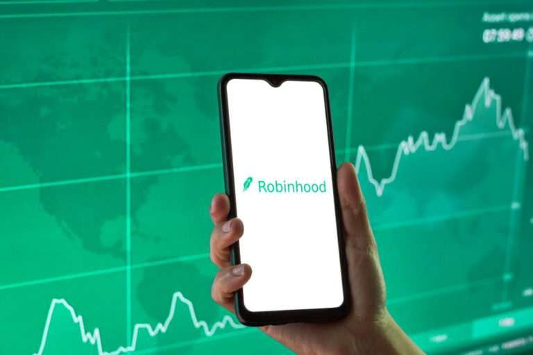a man holding mobile on which screen shows Robinhood with green chart graph