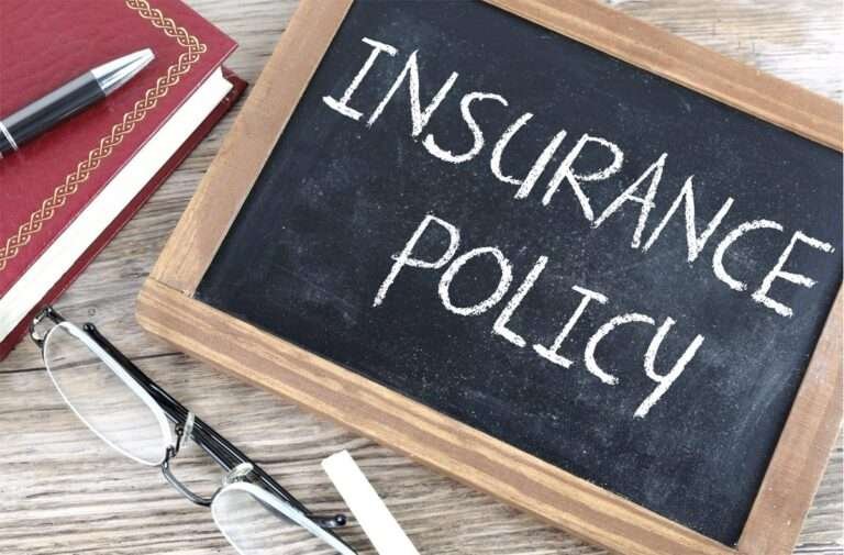 insurance policy written on blackboard with a diary and pen aside